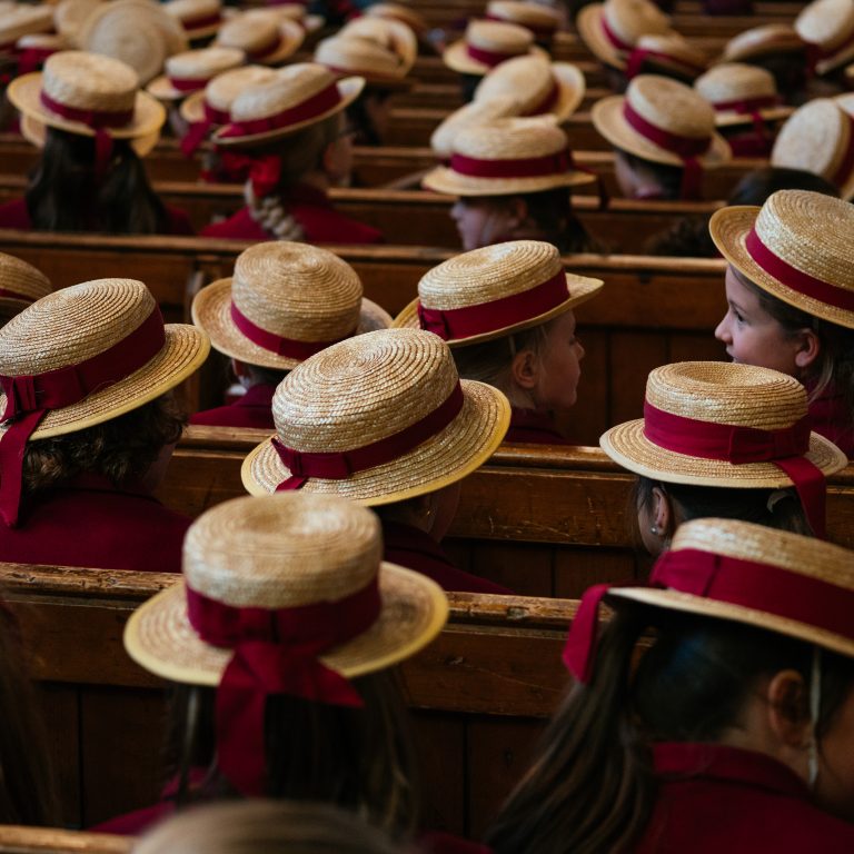 schoolgirls sat in the church area with their hats on