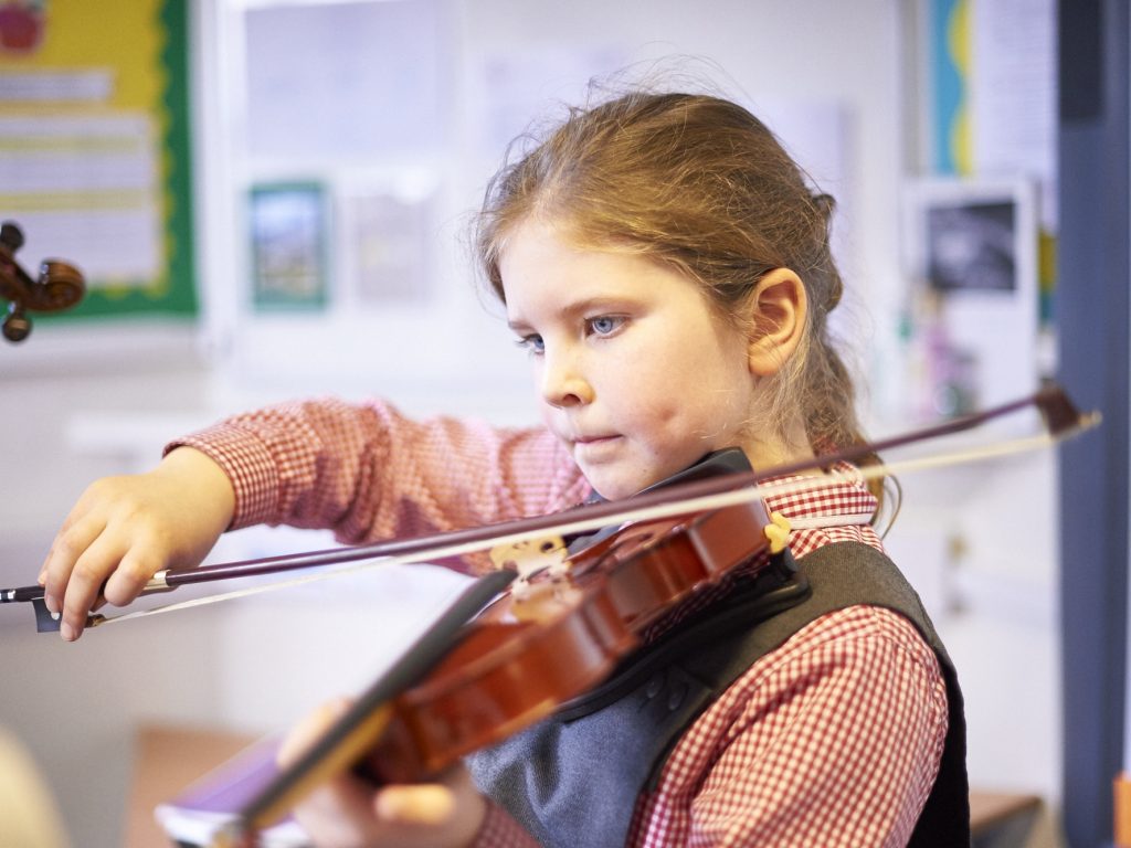 A young girl practicing their violin lessons